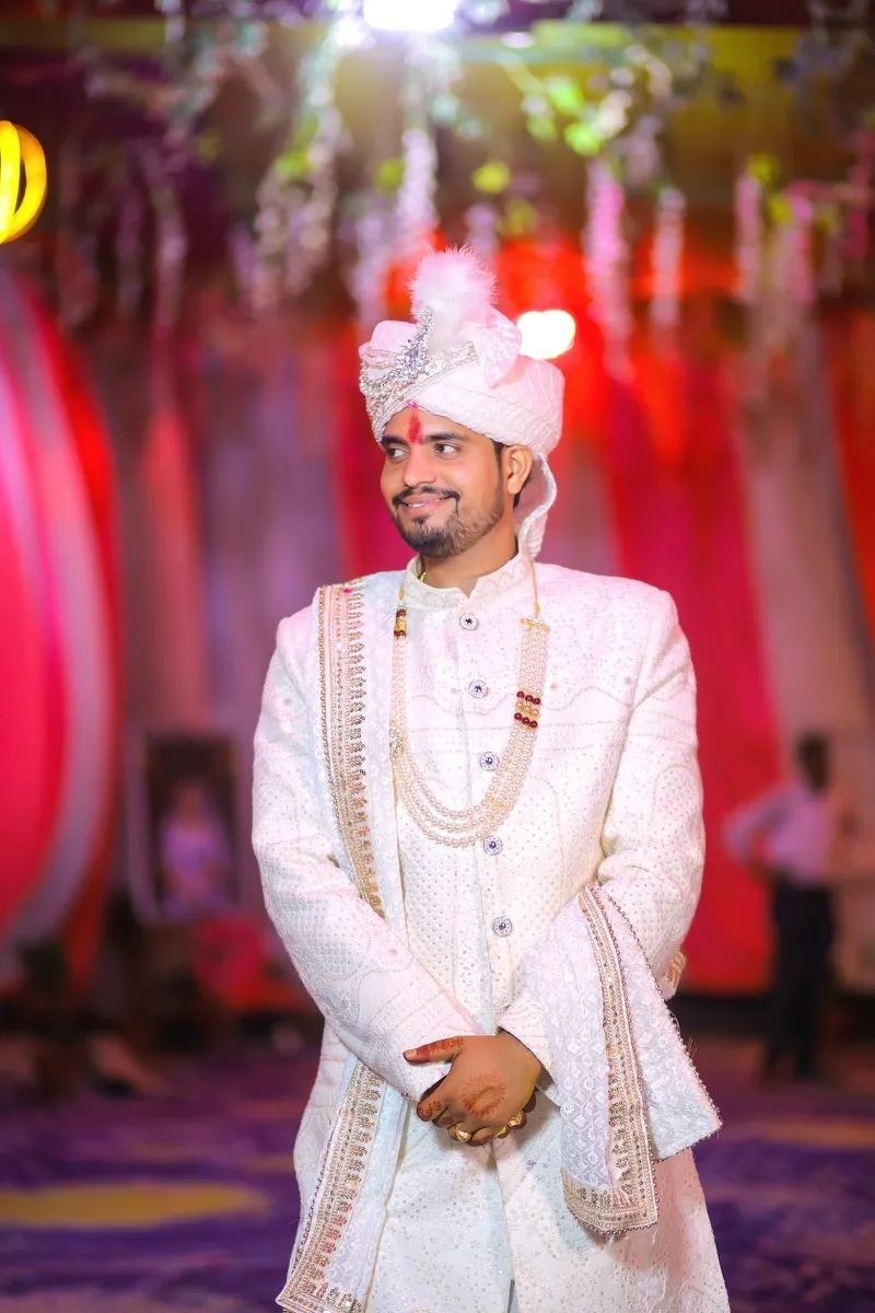 A groom in an embroidered white sherwani and turban